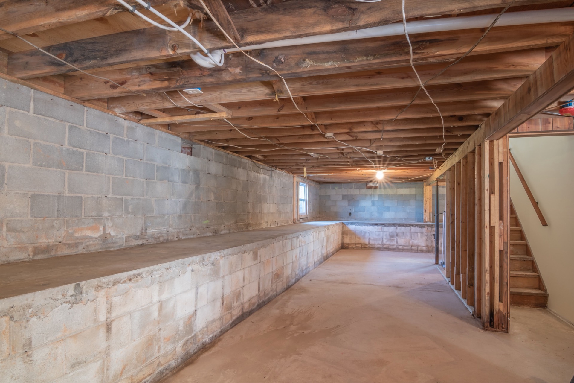 The block foundation wall and floor joists of an unfinished residential basement