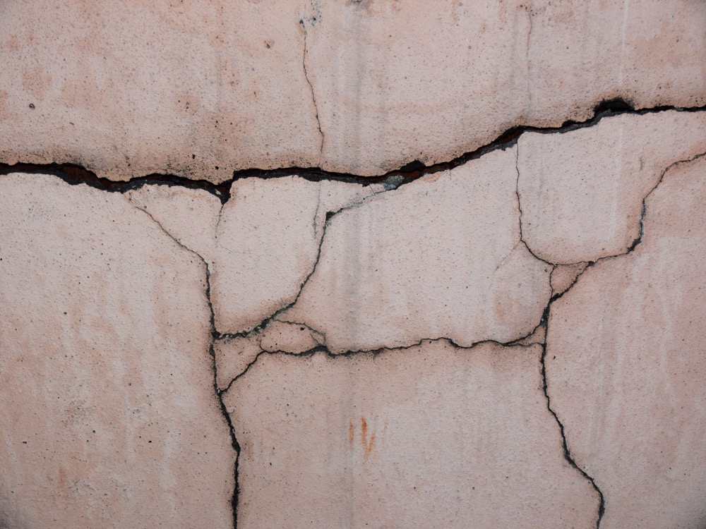 A wide crack running horizontally across a concrete foundation wall